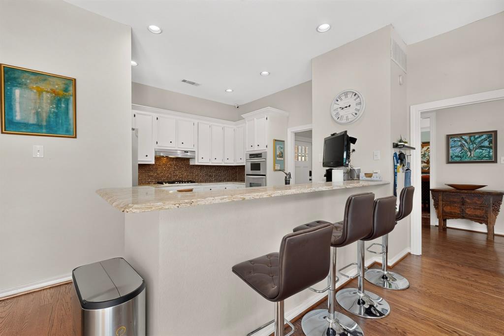 1526 Abrams Road Dallas, TX 75214 - Photo 13 of 38 Kitchen with white cabinetry, built-in microwave, tile backsplash, and a breakfast bar with a light-toned countertop