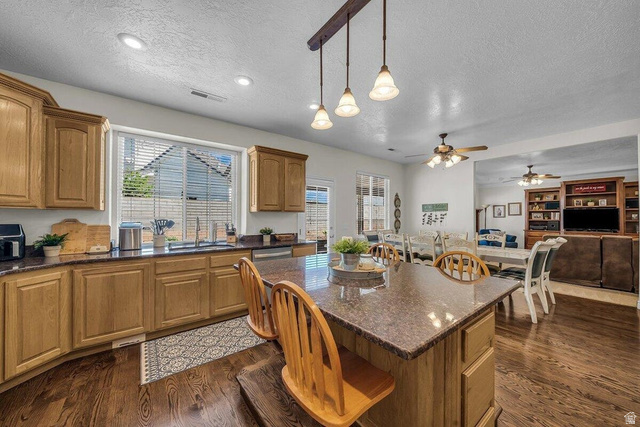 841 1010 S Street St. George, UT 84790 - Photo 33 of 33 Kitchen with dark wood-style floors, dark stone counters, a textured ceiling, a kitchen bar, and open floor plan