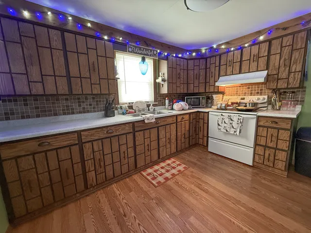 a kitchen with stainless steel appliances granite countertop a sink stove and wooden cabinets