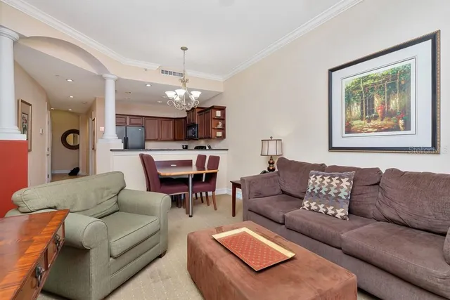a living room with furniture kitchen view and a chandelier