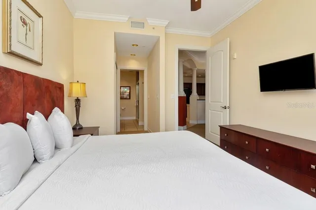 a bedroom with a bed and a flat tv screen on dresser