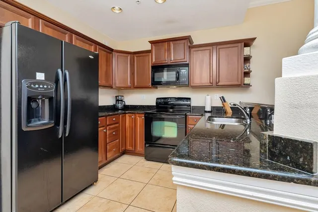 a kitchen with stainless steel appliances granite countertop a refrigerator a stove and a sink