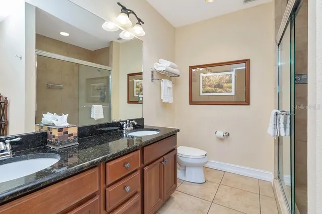 a spacious bathroom with a granite countertop sink a toilet a mirror and shower