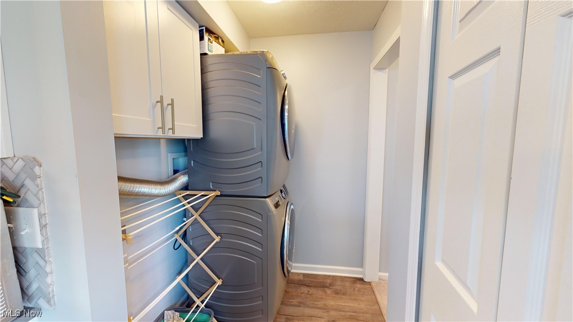 3044 Gale Road Willoughby, OH 44094 - Photo 11 of 30 Clothes washing area featuring hardwood / wood-style flooring, cabinets, and stacked washing maching and dryer