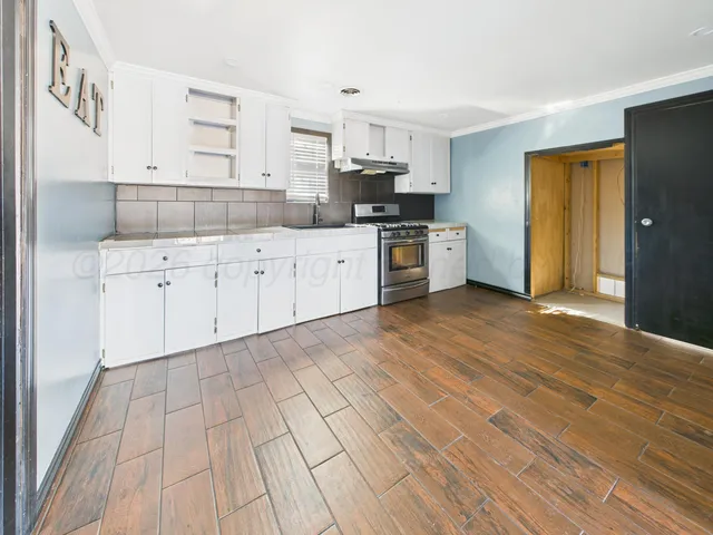 a kitchen with stainless steel appliances granite countertop a sink cabinets and wooden floor