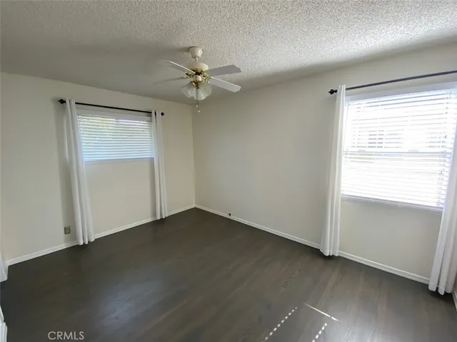 an empty room with wooden floor closet and windows