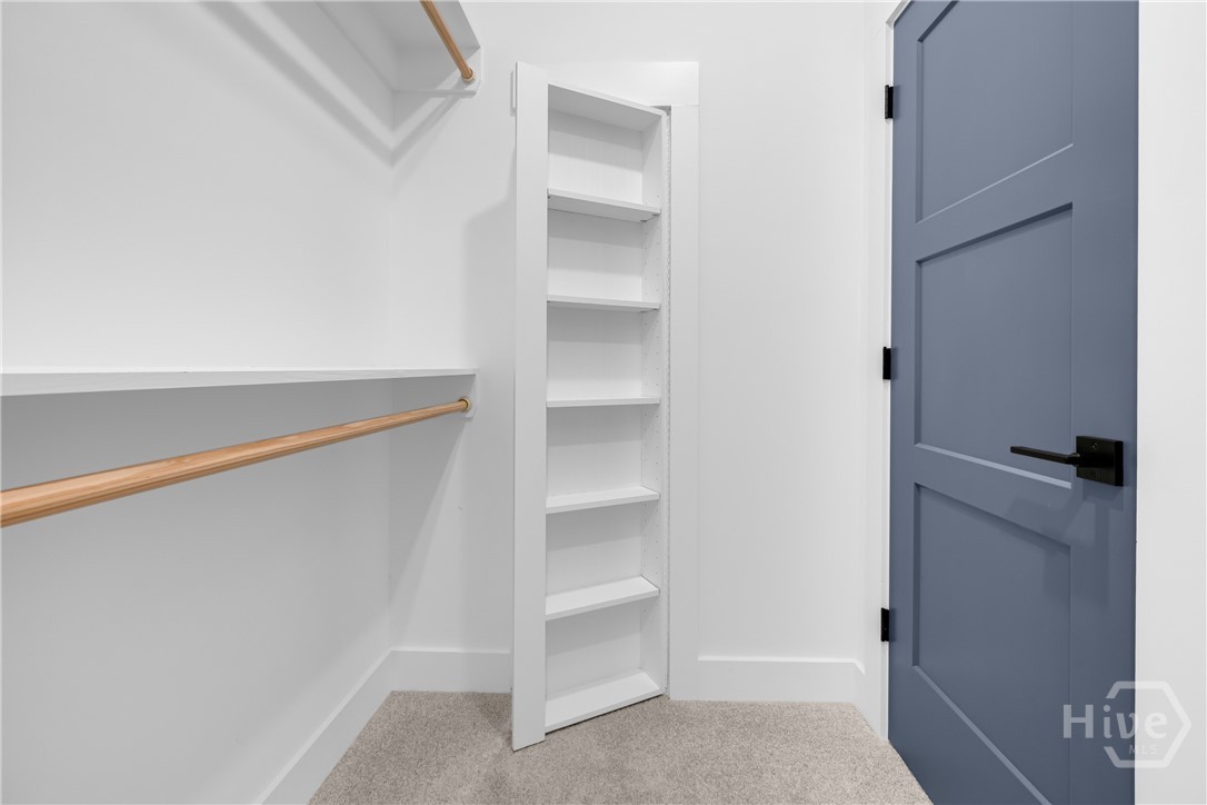 2476 St Martin Way Monroe, GA 30656 - Photo 47 of 75 White built-in shelving unit, natural wood-finish hanging rods, and a three-panel door with matte black hardware