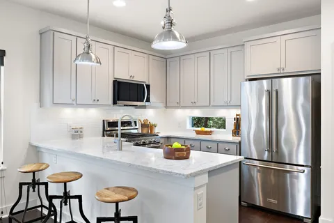 a kitchen with stainless steel appliances a refrigerator a stove a sink and white cabinets