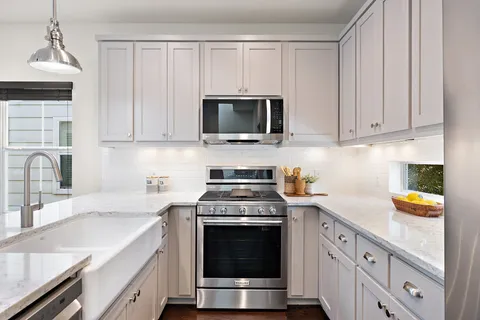 a kitchen with granite countertop a stove a sink and a microwave