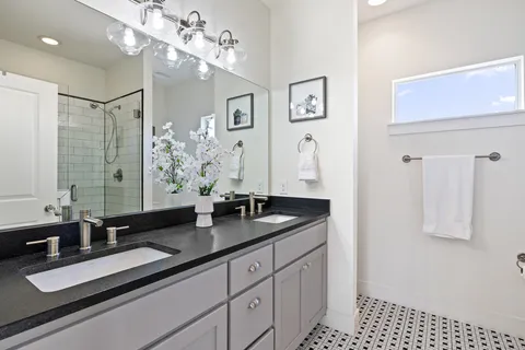 a bathroom with a sink double vanity granite and a shower