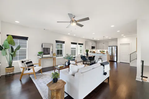 a living room with furniture kitchen view and a wooden floor