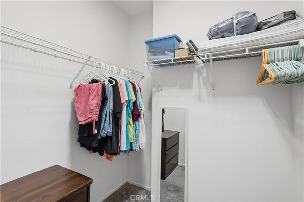 a view of walk in closet with clothes and shoes