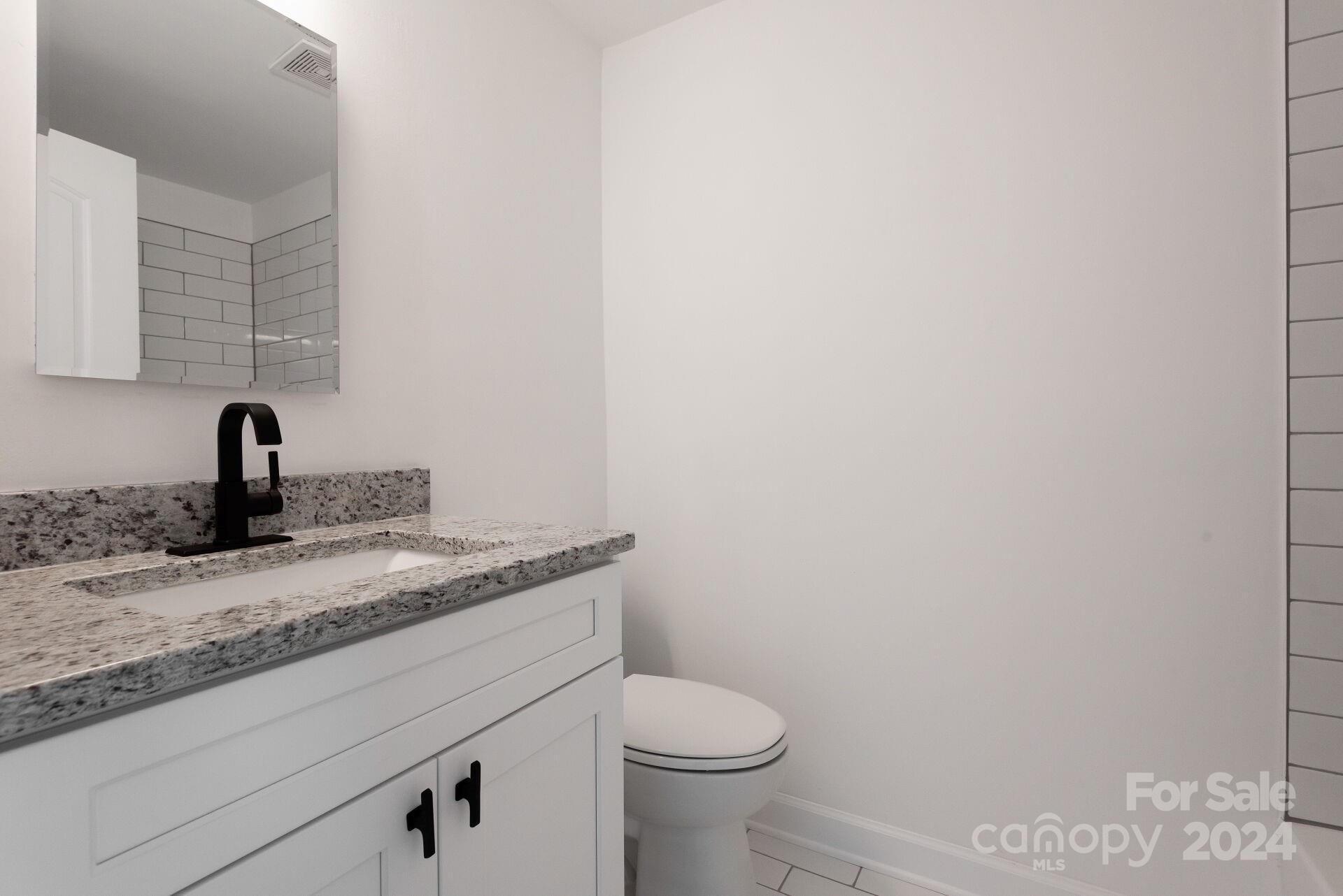 7516 Pebblestone Drive, Unit E Charlotte, NC 28212 - Photo 16 of 21 a bathroom with a granite countertop sink toilet and mirror