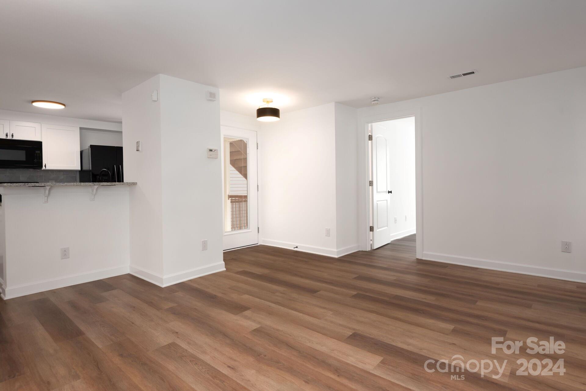 7516 Pebblestone Drive, Unit E Charlotte, NC 28212 - Photo 4 of 21 a view of empty room with wooden floor and windows