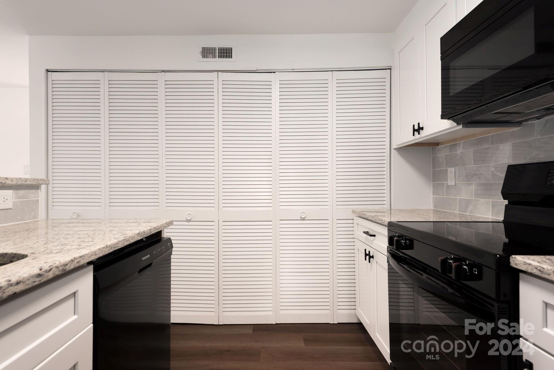 7516 Pebblestone Drive, Unit E Charlotte, NC 28212 - Photo 7 of 21 a kitchen with granite countertop white cabinets and black appliances