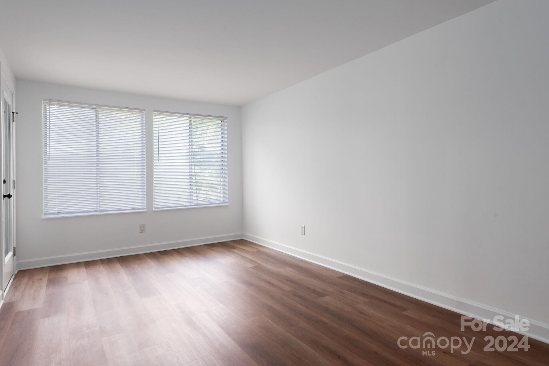 7516 Pebblestone Drive, Unit E Charlotte, NC 28212 - Photo 8 of 21 a view of an empty room with wooden floor and a window