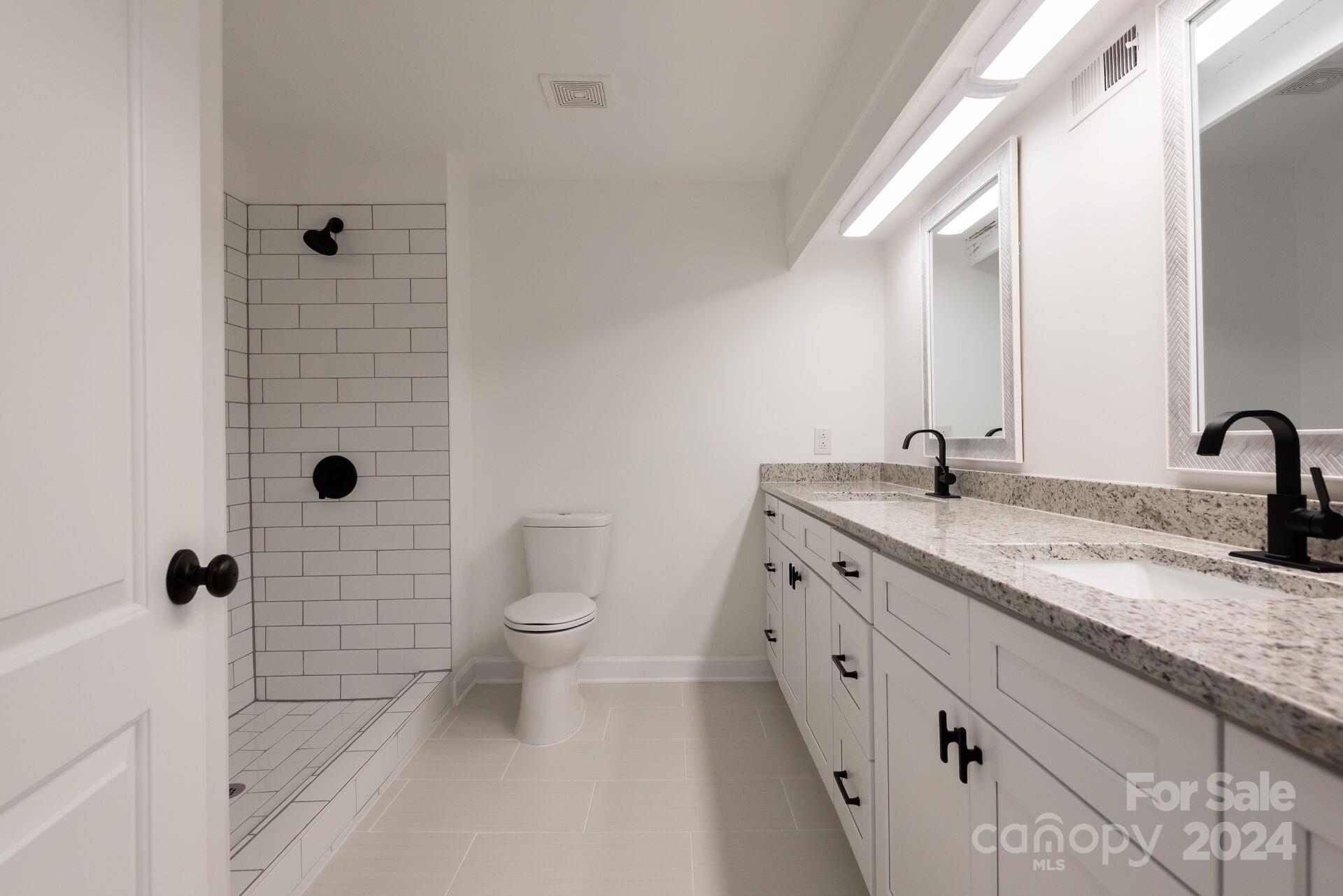 7516 Pebblestone Drive, Unit E Charlotte, NC 28212 - Photo 10 of 21 a bathroom with a granite countertop sink a toilet and a mirror
