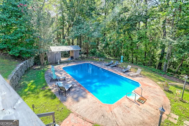 a view of a swimming pool with a patio and a yard