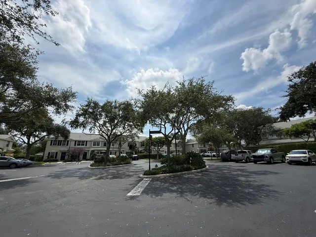 a view of road with card parked on side and retail shops