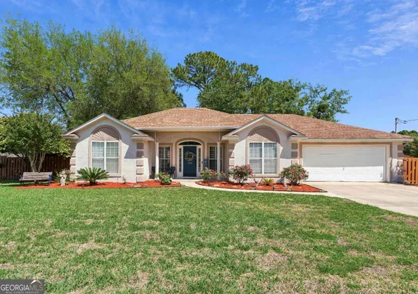 a front view of a house with a big yard and large trees