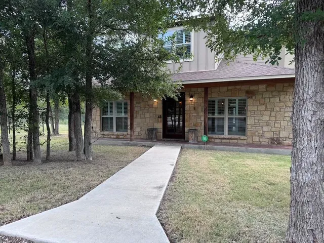 a view of a brick house with large windows and large trees