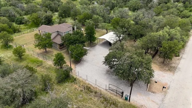 an aerial view of residential house with outdoor space and trees all around