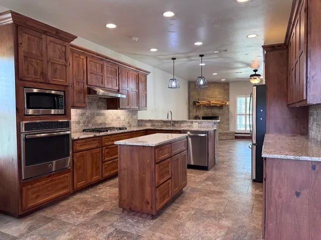 a large kitchen with stainless steel appliances granite countertop wooden cabinets a sink and a stove