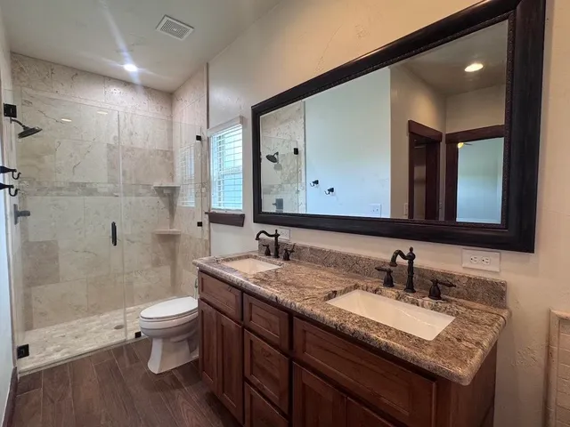 a bathroom with a granite countertop sink a toilet and a mirror