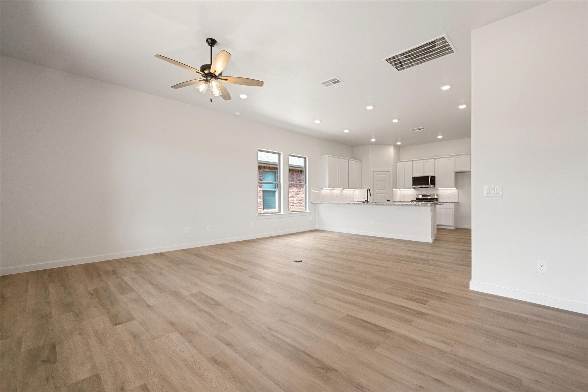 313 East 23rd Street Wolfforth, TX 79382 - Photo 11 of 22 a view of an empty room with wooden floor and a kitchen
