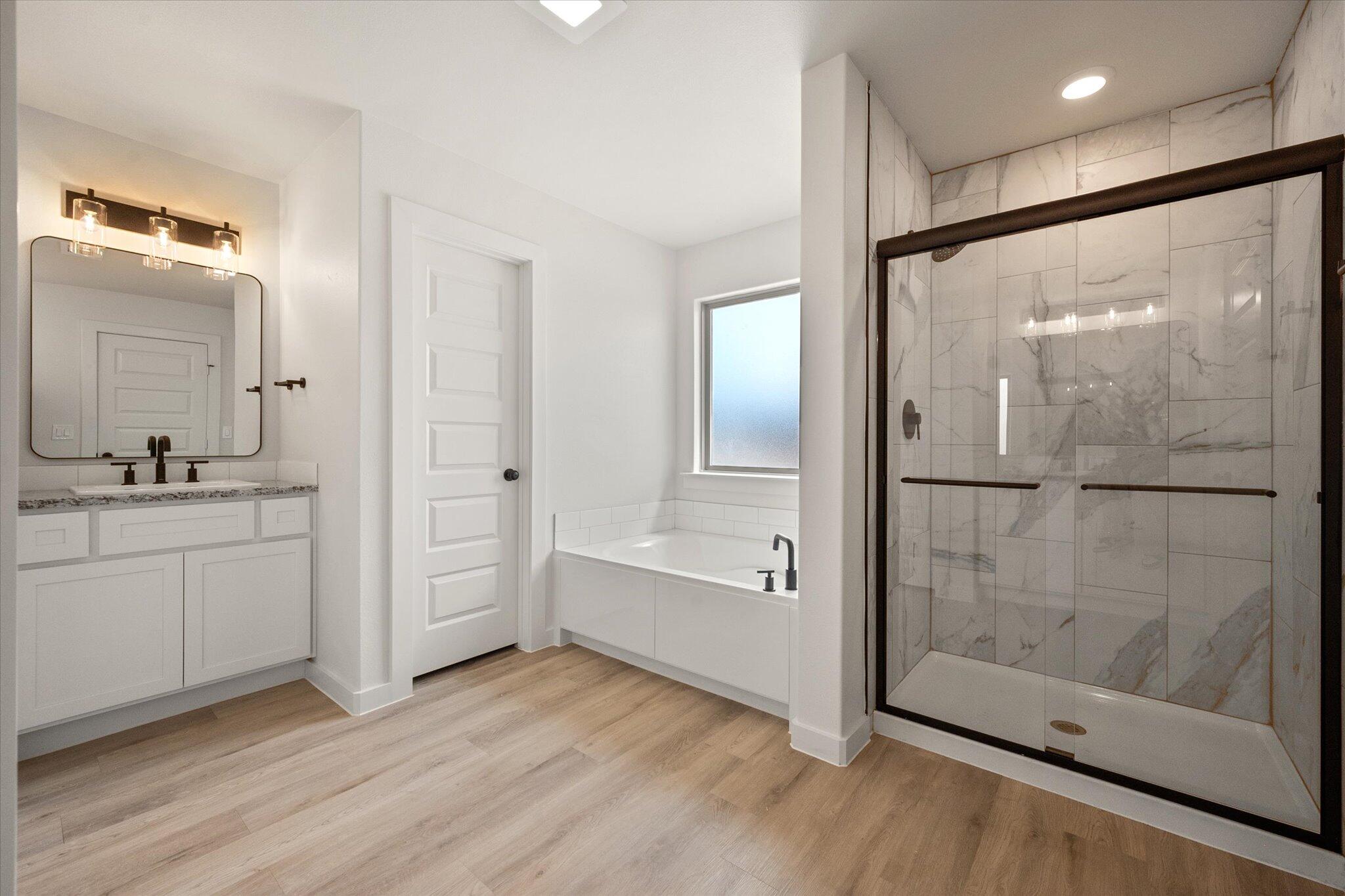 313 East 23rd Street Wolfforth, TX 79382 - Photo 15 of 22 a bathroom with a double vanity sink a mirror and a bathtub