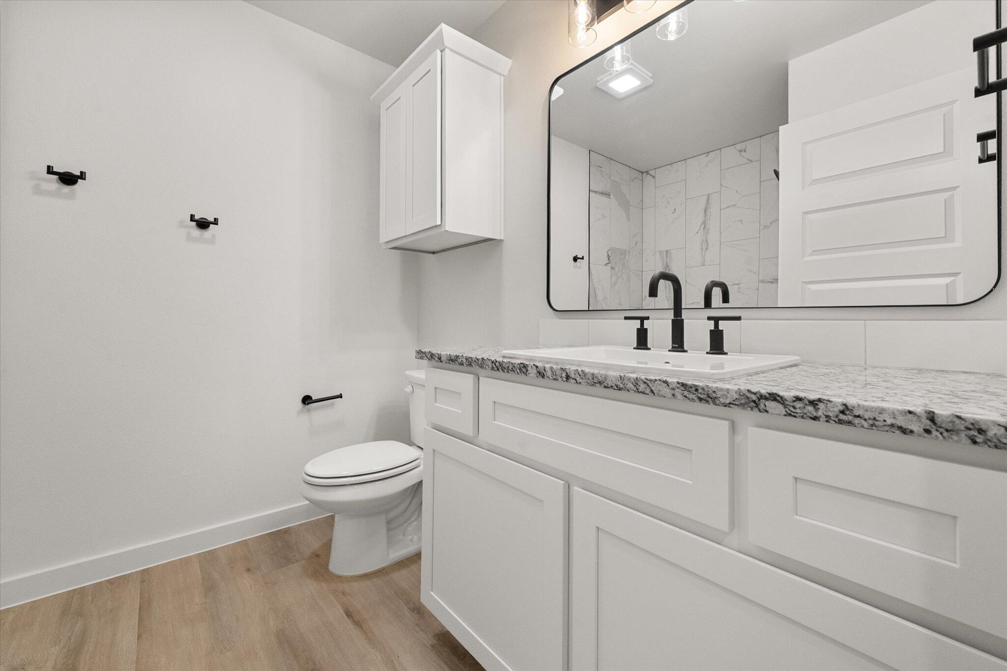 313 East 23rd Street Wolfforth, TX 79382 - Photo 20 of 22 a bathroom with a granite countertop sink a toilet and a mirror