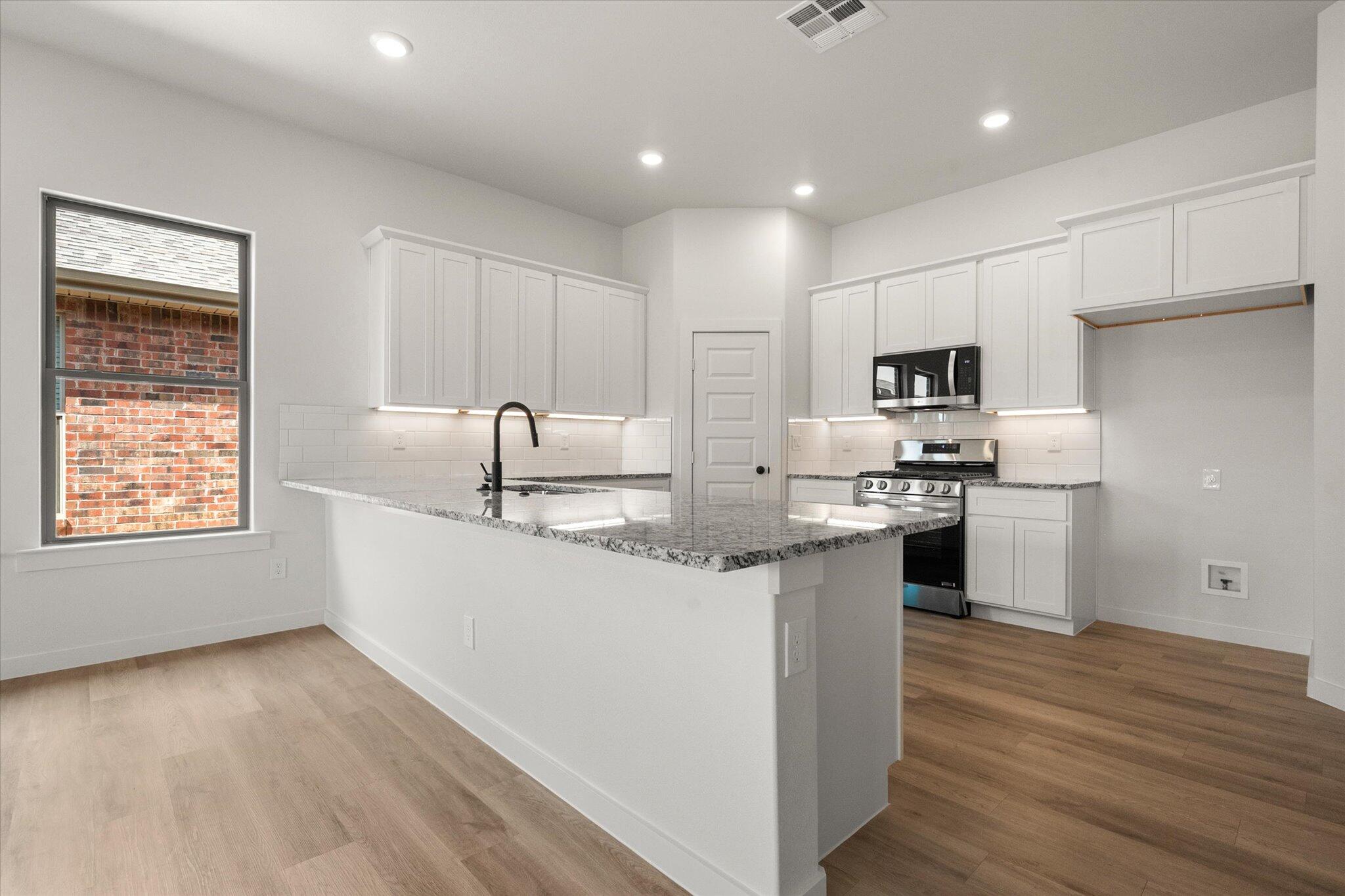 313 East 23rd Street Wolfforth, TX 79382 - Photo 5 of 22 a kitchen with kitchen island a sink stainless steel appliances and cabinets