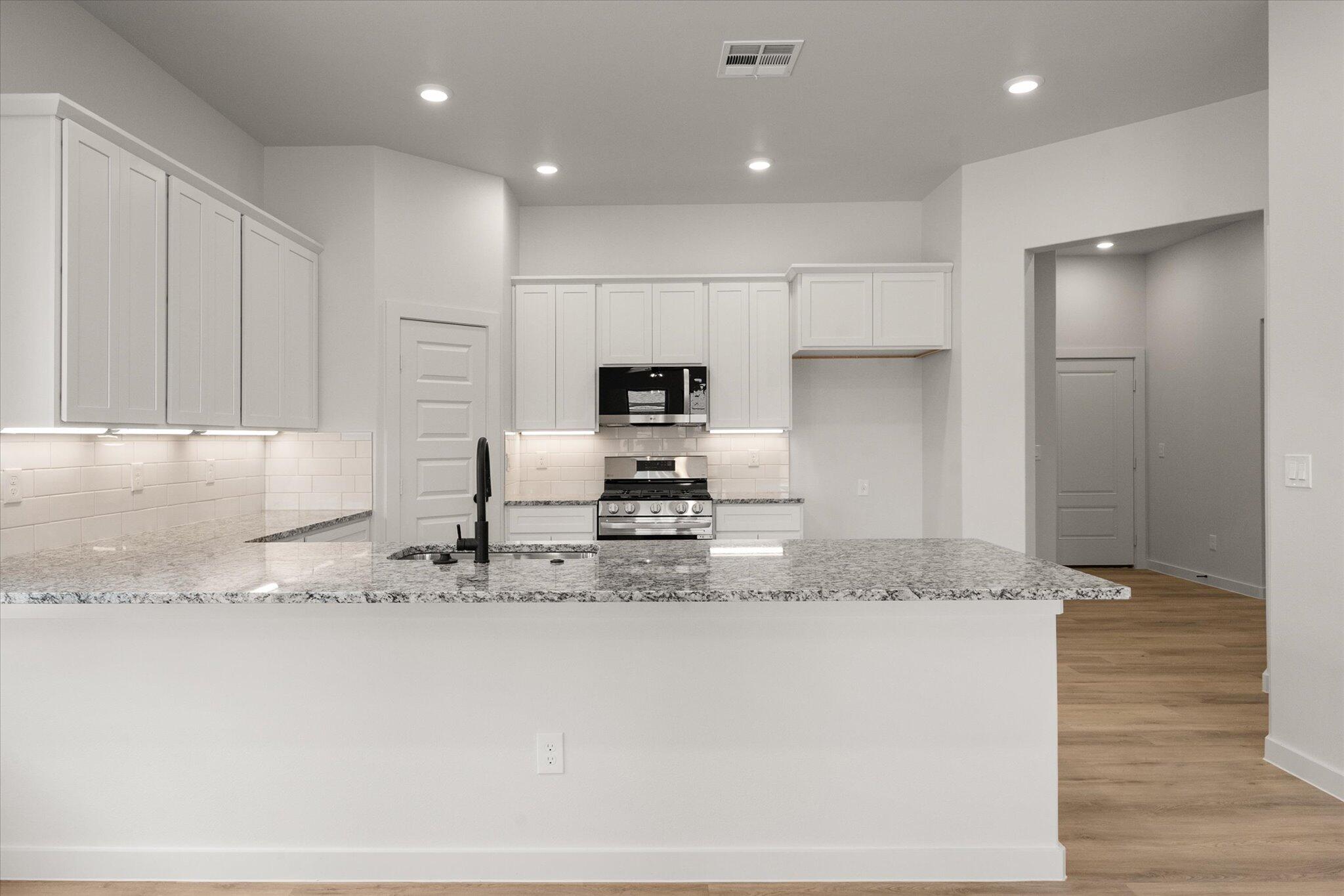 313 East 23rd Street Wolfforth, TX 79382 - Photo 6 of 22 a kitchen with stainless steel appliances granite countertop a sink a stove and a refrigerator