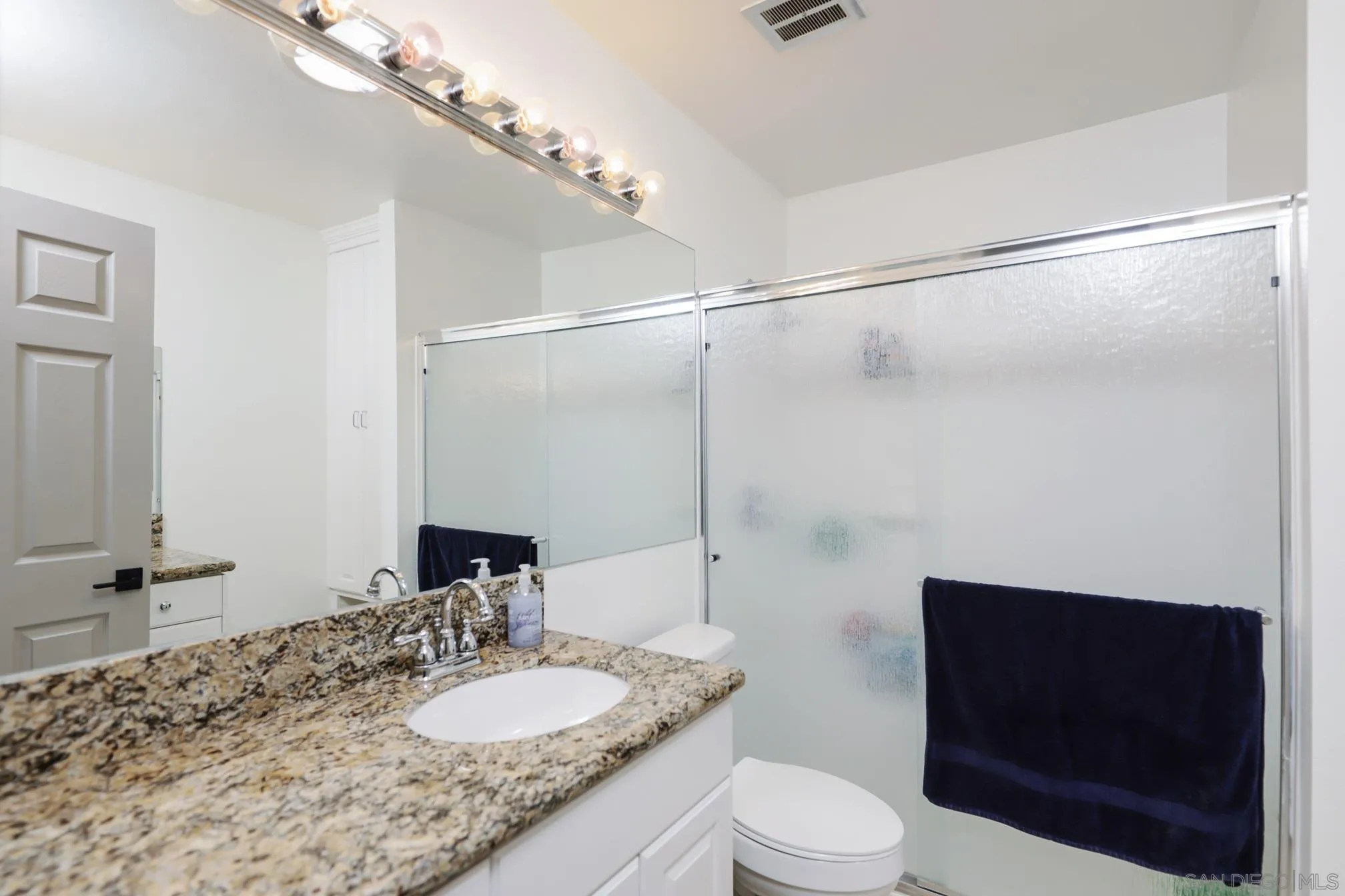 13134 Acton Avenue Poway, CA 92064 - Photo 16 of 37 a bathroom with a granite countertop sink toilet a mirror and shower