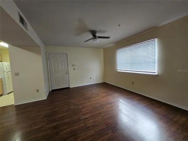 an empty room with wooden floor cabinet and windows