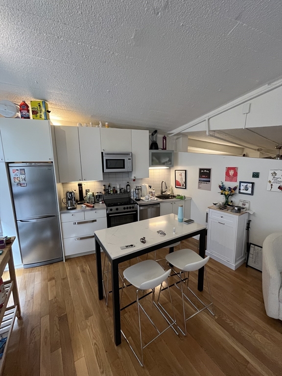 12 Stoneholm Street, Unit 322 Boston, MA 02115 - Photo 8 of 33 a kitchen with a dining table chairs and a refrigerator