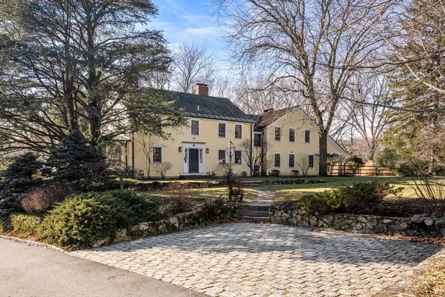 a view of a white house with a yard covered with trees