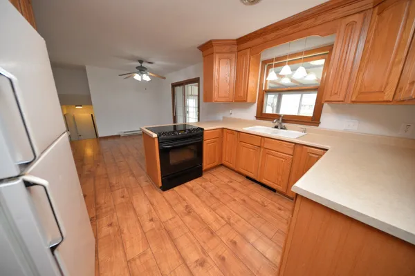 a kitchen with stainless steel appliances granite countertop a sink a stove a refrigerator a washer dryer and white cabinets