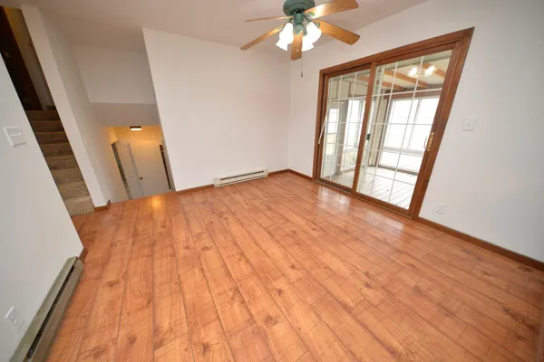 a view of an empty room with wooden floor and a window