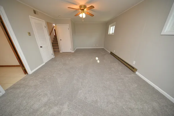 an empty room with a ceiling fan and window