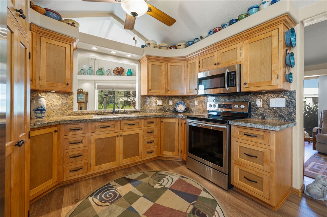 2000 Ramar Road, Unit 665 Bullhead City, AZ 86442 - Photo 16 of 83 Kitchen featuring custom wood cabinetry, granite countertops, tile backsplash, recessed lighting, and stainless steel range and microwave.