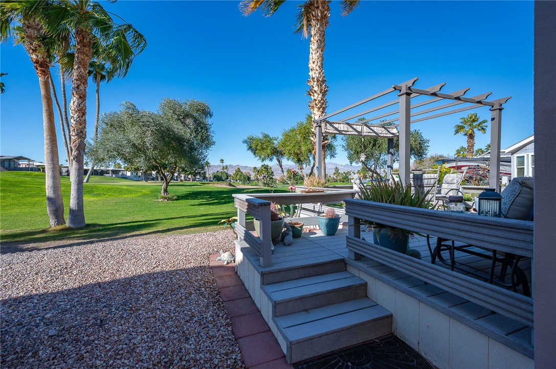 2000 Ramar Road, Unit 665 Bullhead City, AZ 86442 - Photo 46 of 83 Elevated rear deck with steps leading directly to the golf course, offering open greenbelt views and seamless indoor-outdoor living.