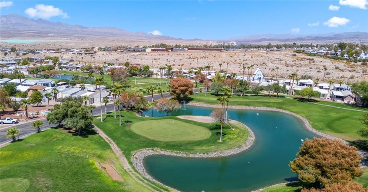 2000 Ramar Road, Unit 665 Bullhead City, AZ 86442 - Photo 79 of 83 Aerial view of the golf course featuring manicured greens, water feature, cart paths, and scenic desert mountain backdrop within Riverview RV Resort.