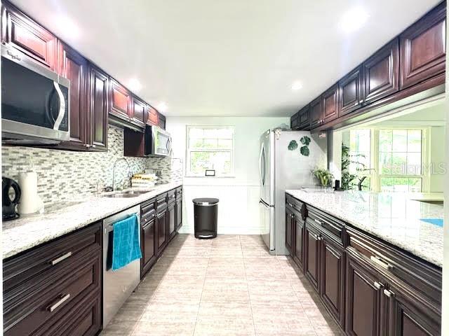 946 Virginia Street, Unit 104 Dunedin, FL 34698 - Photo 36 of 64 a large kitchen with stainless steel appliances granite countertop a large stove a sink dishwasher and a microwave oven with large wooden cabinets