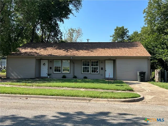 a front view of a house with a garden and trees
