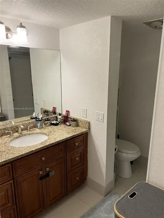 a bathroom with a granite countertop sink toilet and mirror