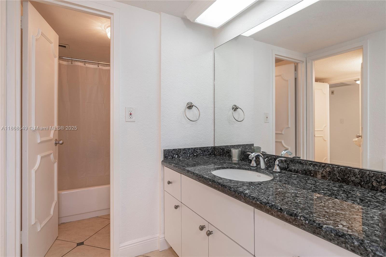 5701 Collins Avenue, Unit 405 Miami Beach, FL 33140 - Photo 11 of 18 a bathroom with a granite countertop sink and a mirror