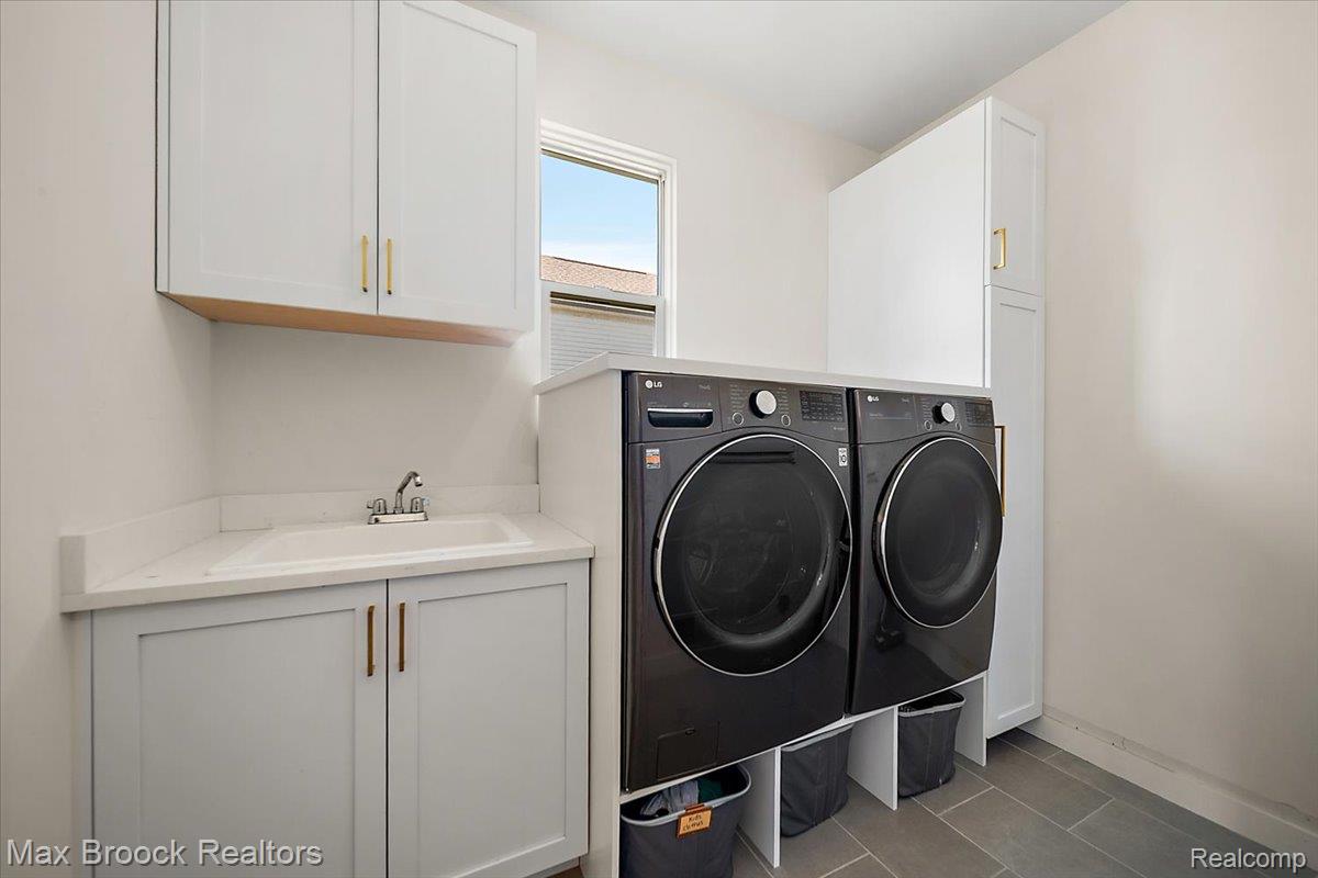 1942 Nottingham Drive Rochester, MI 48307 - Photo 28 of 97 Laundry room featuring built-in cabinetry, a utility sink with a stone-finish countertop, and durable tile flooring