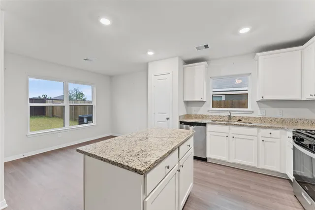 a kitchen with stainless steel appliances granite countertop a refrigerator a stove top oven a sink and dishwasher with wooden floor