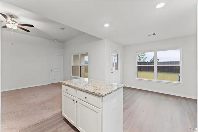 an empty room with chandelier fan and windows
